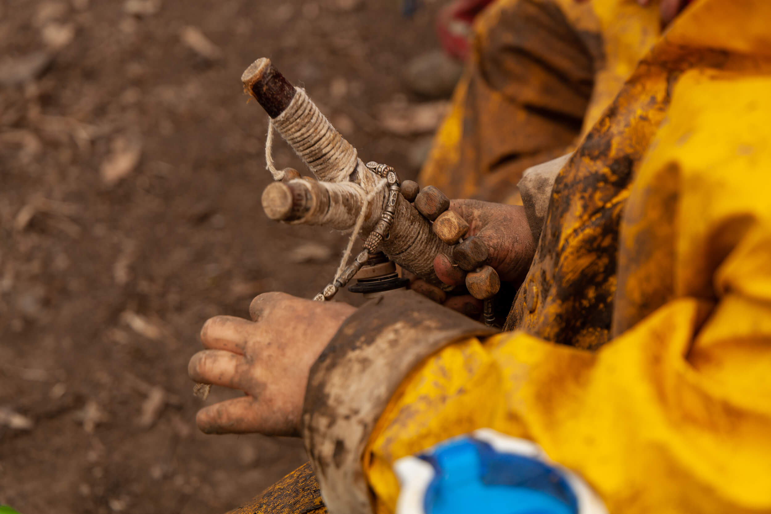 Muddy hands holding a wooden toy