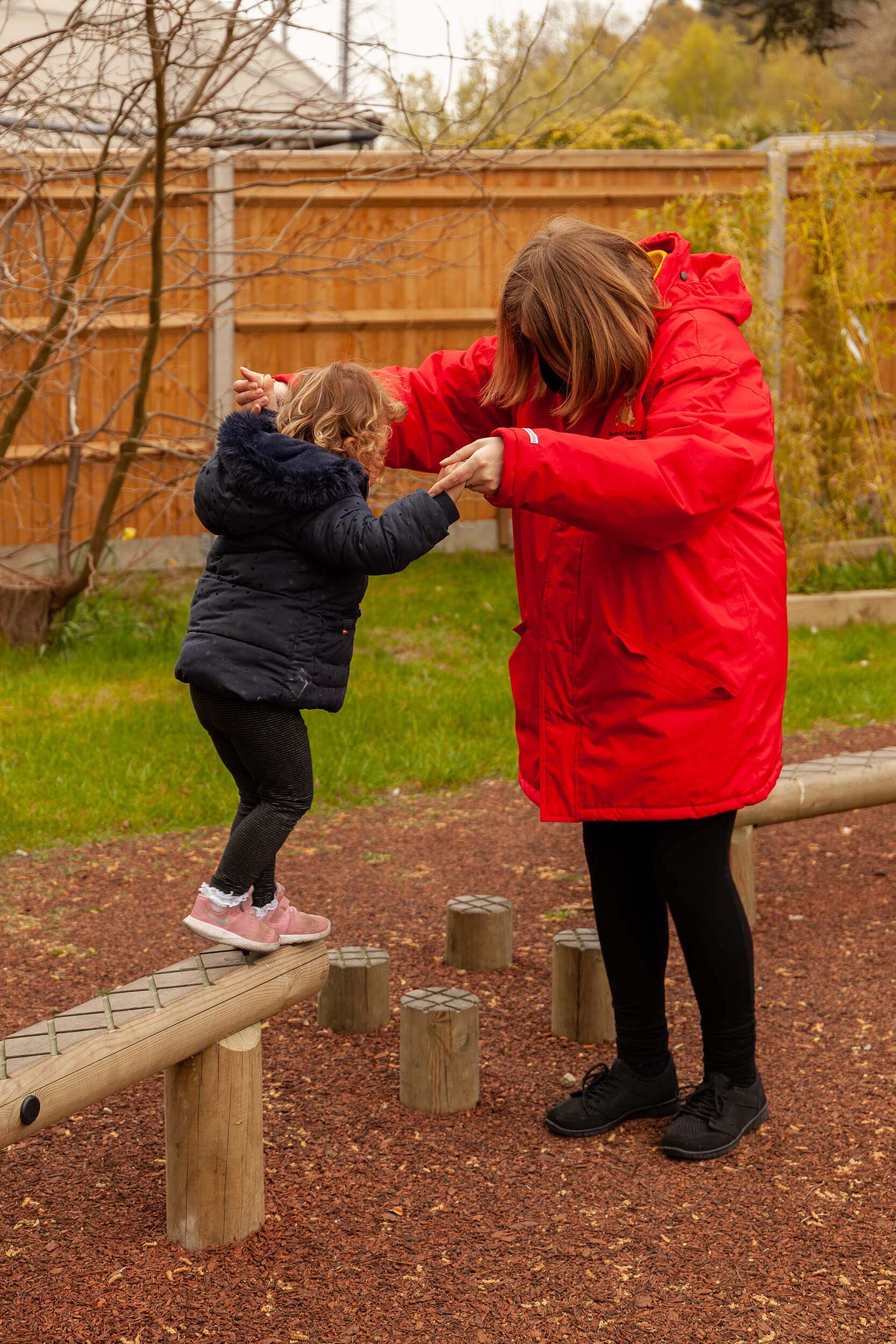 Girl being helped across balance beams