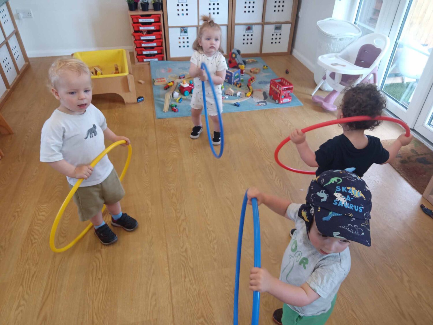 Group of young children hoola hooping in a play room