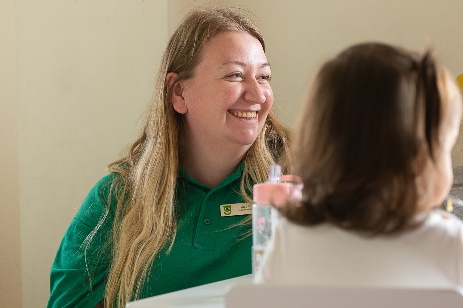 Nursery carer smiling with toddler