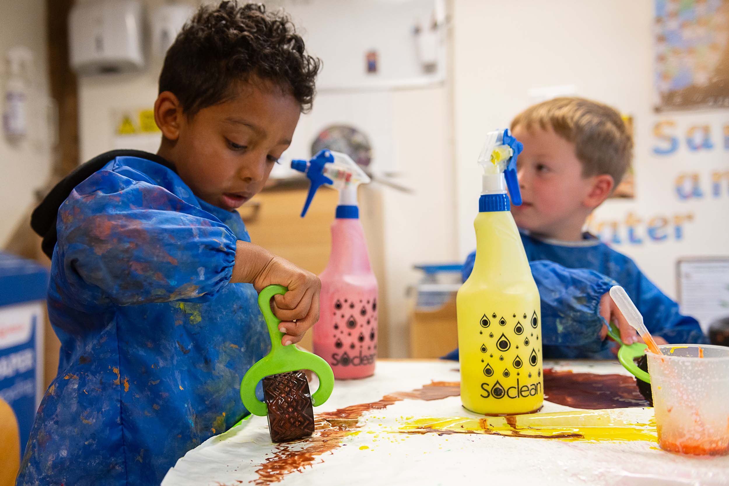 two little boys paining with paint rollers and spray bottles