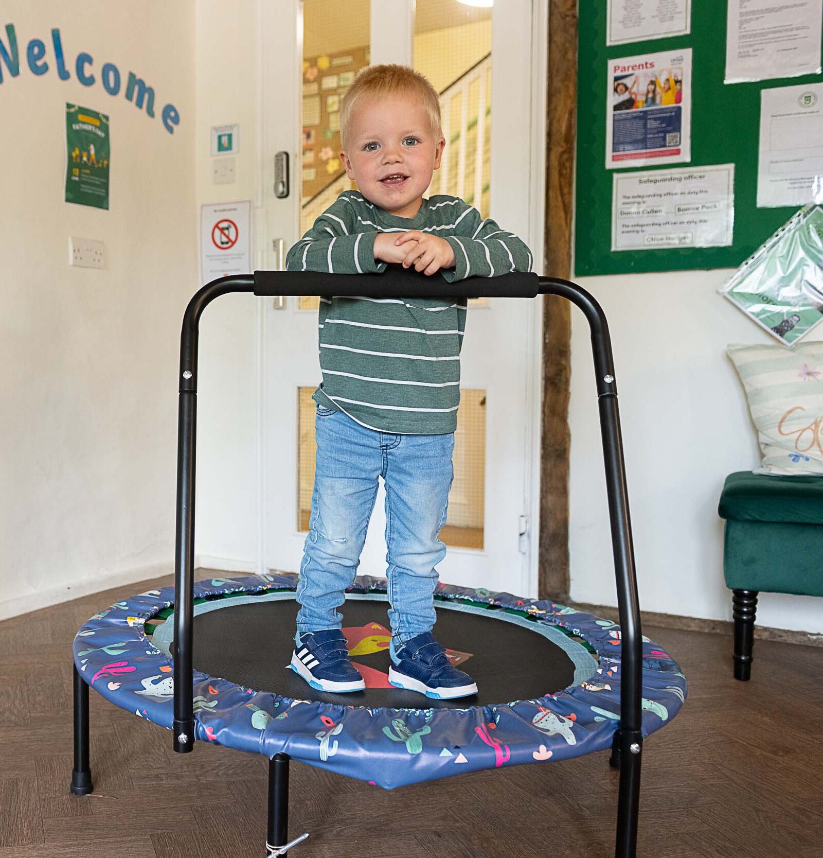 Young boy standing on an assisted mini round trampoline