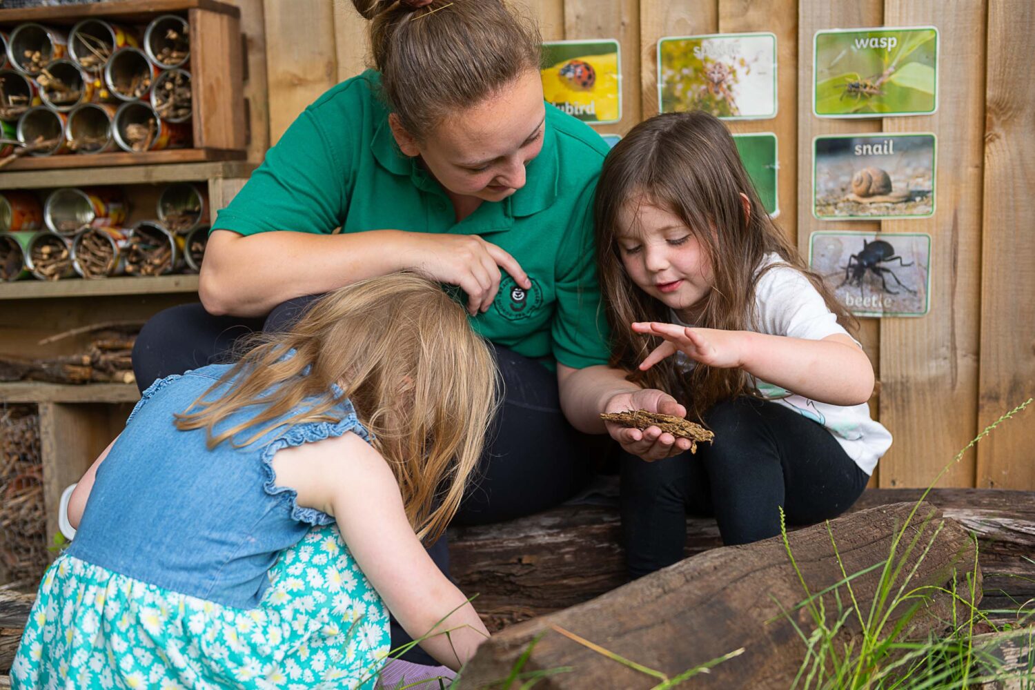 Member of staff holding some bark in her hand, showing to little girls