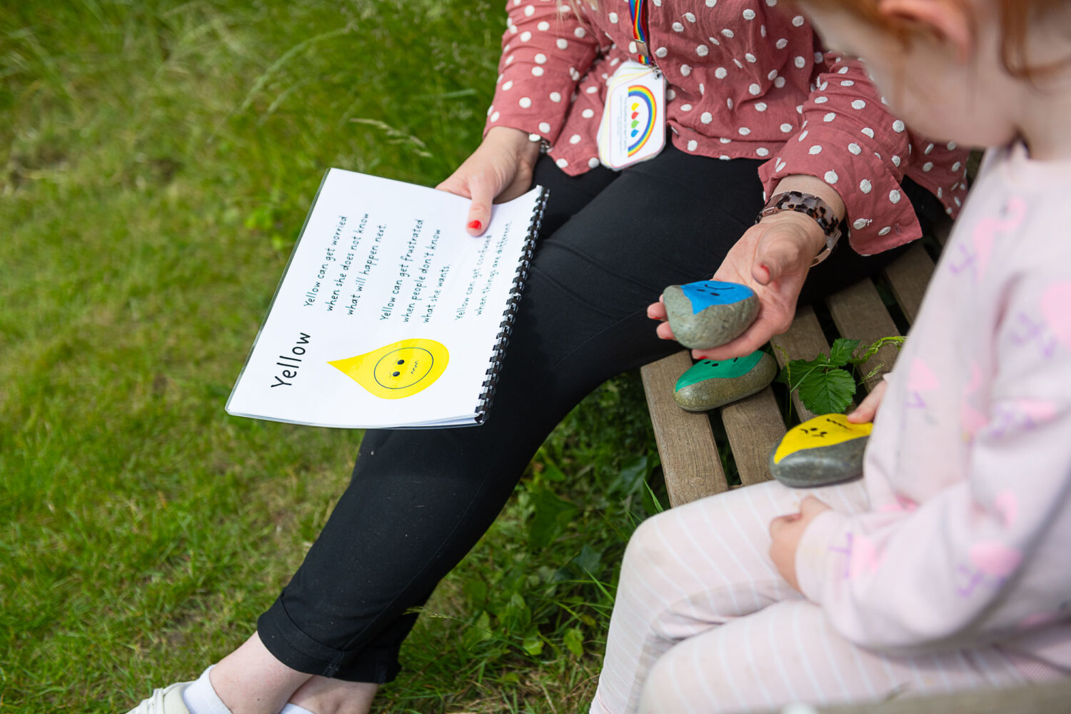 A SEN staff member talking through pebbles painted with different emotions, refferring to a booklet
