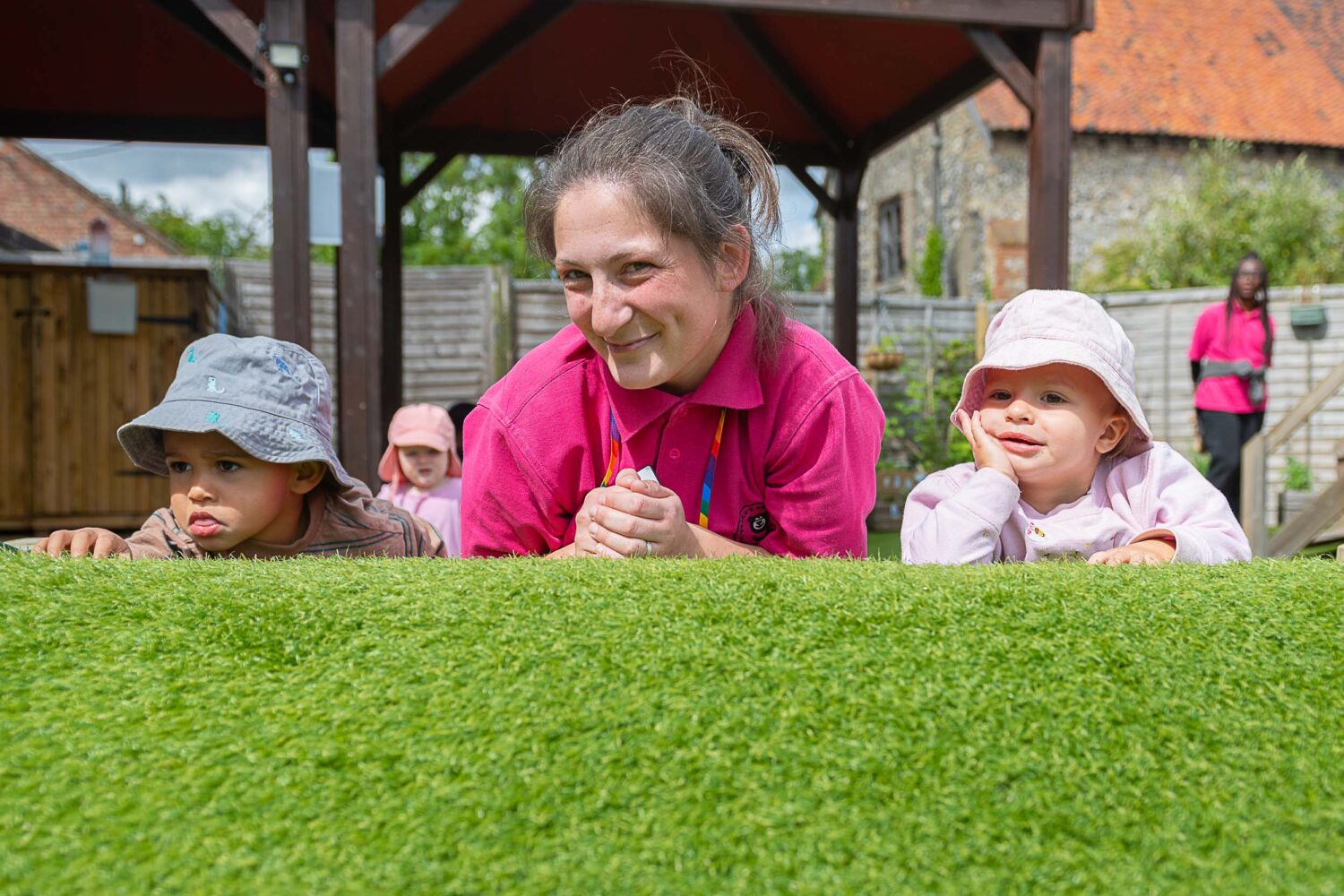 A member of staff laying on the floor with two you children, smiling