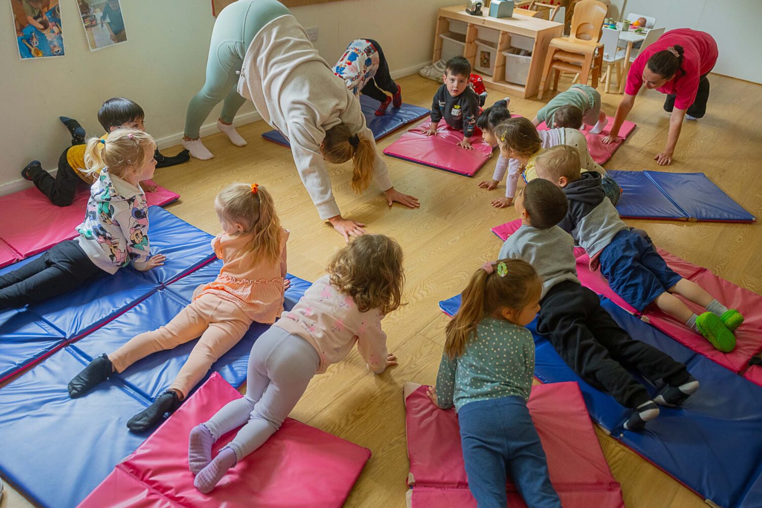 group of children doing stretches on matts with members of staff