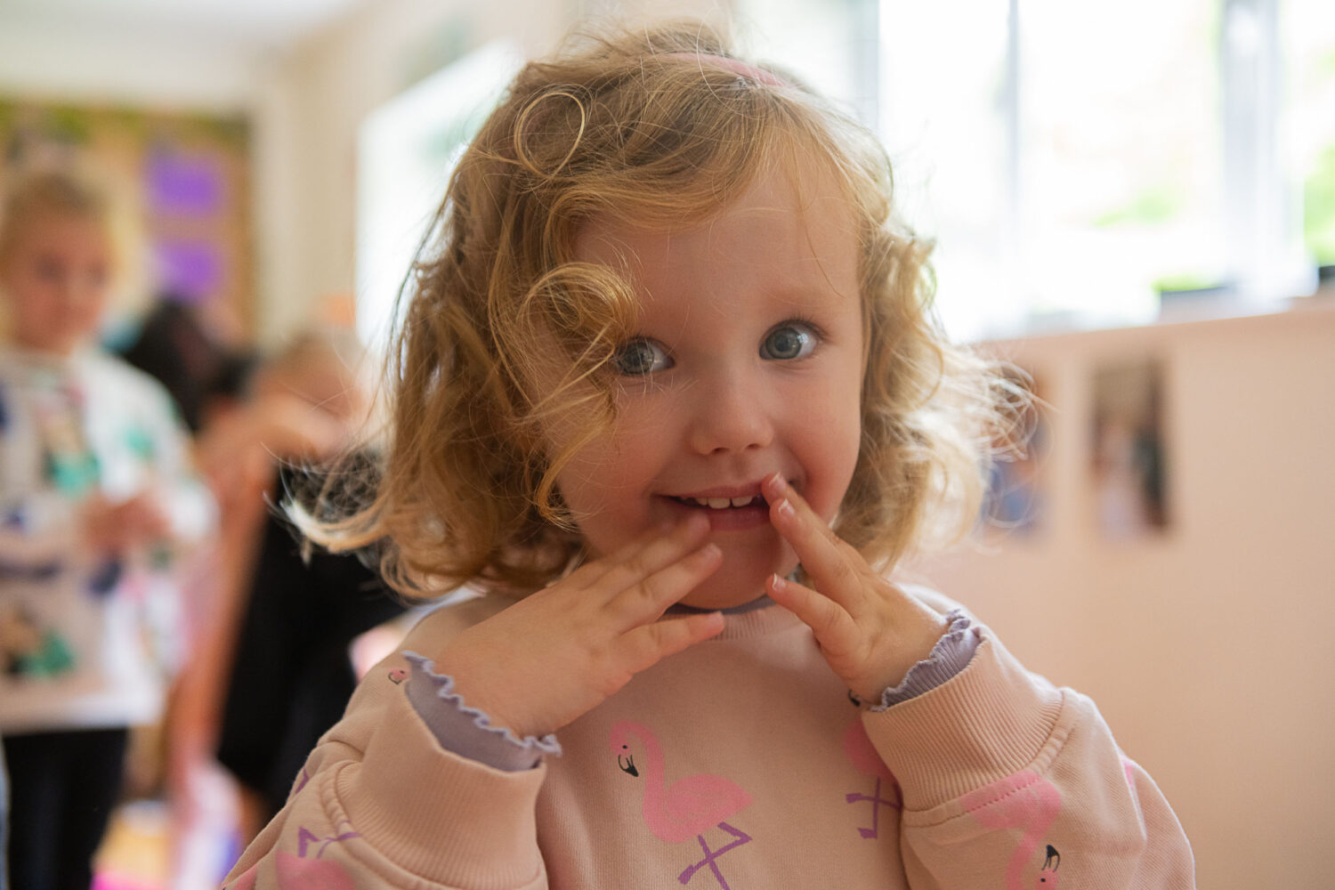 little girl smiling, holding both her hands to her face