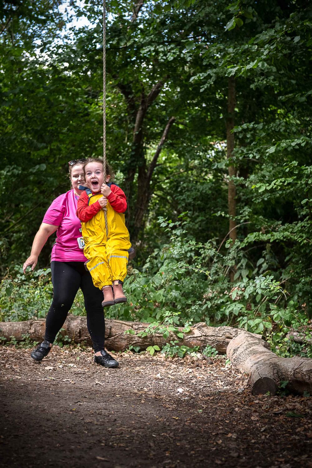 A member of staff swinging a very excited girl on the rope swing
