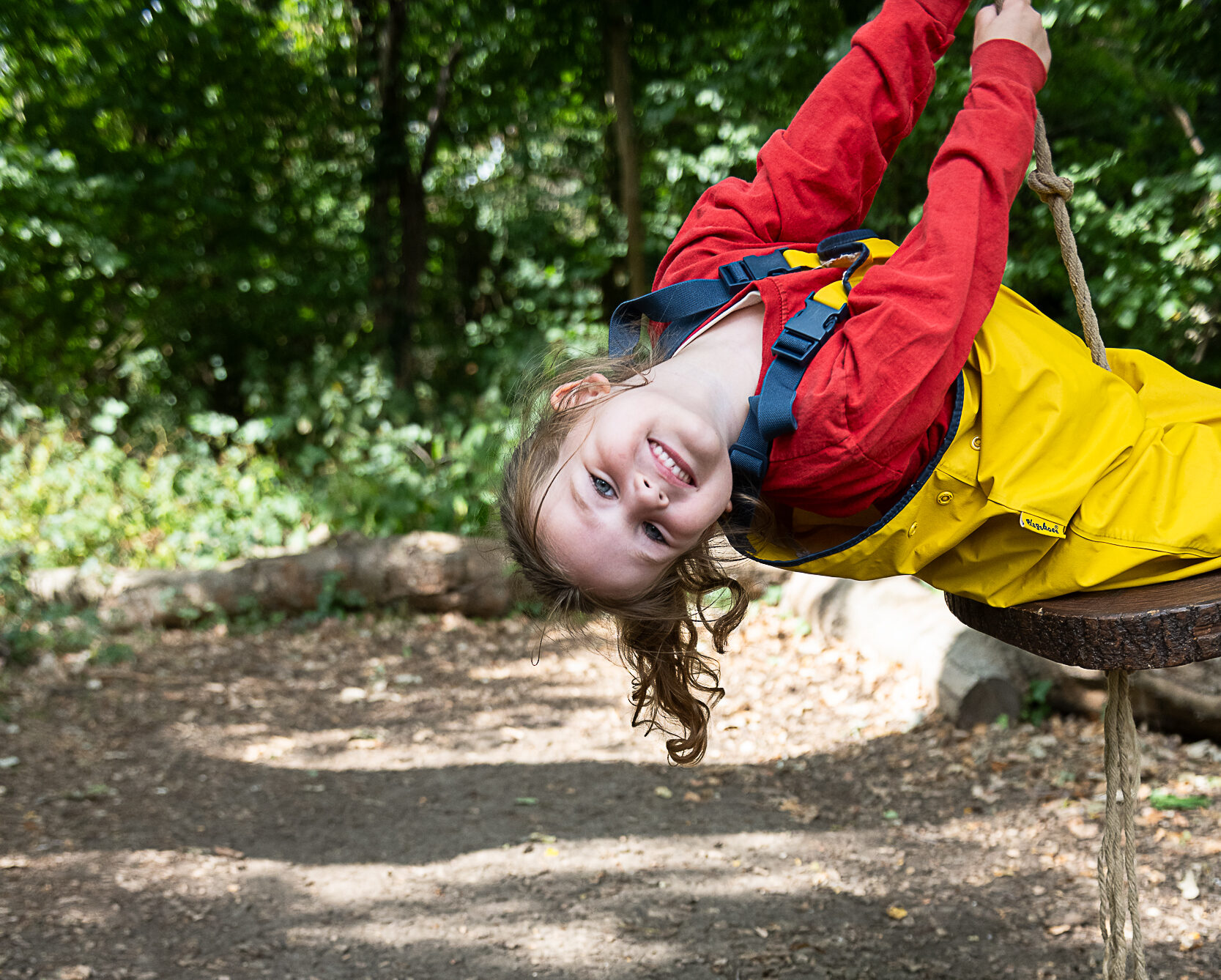 Young Girl hanging upside down on a rope swing