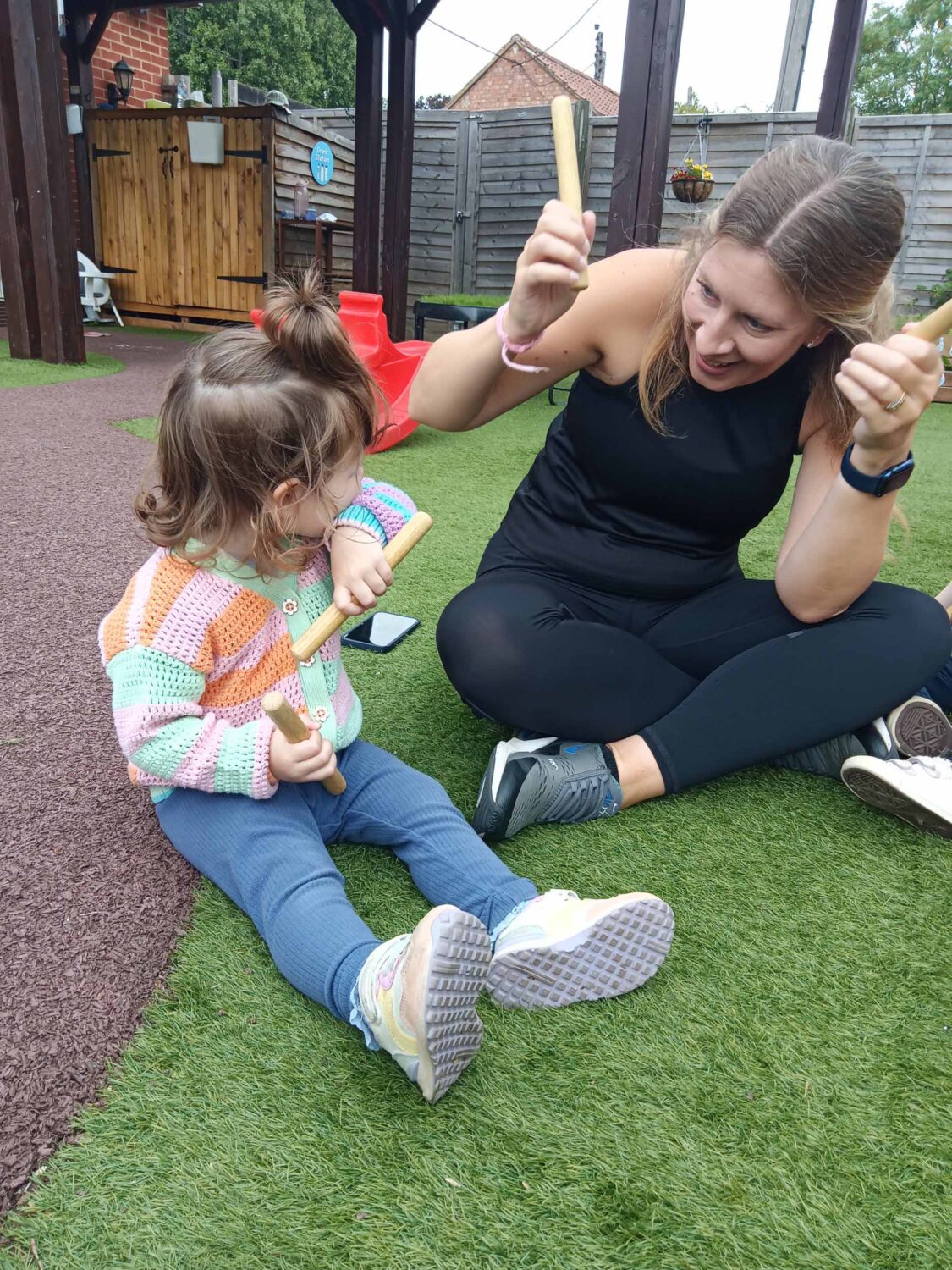 A staff member sat in the play area with a little girl, pretending to drum